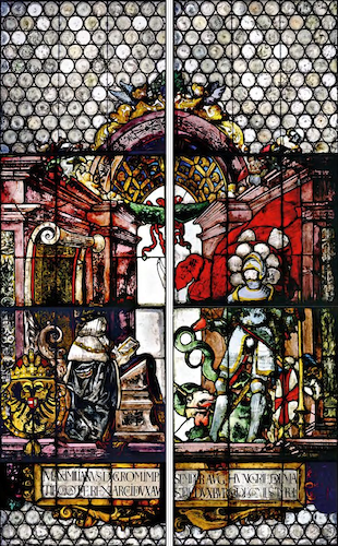 In the left window, the Emperor is depicted in a richly decorated interior scene. Arrayed in a blue cloak with ermine collar, he kneels in a prie-dieu, gazing at the patron saint of the city of Freiburg, St George. The imperial coat of arms shown next to him is embellished with the neck chain of the Order of the Golden Fleece and adorned with the Austrian imperial crown.