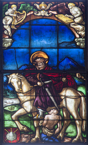 In the right-hand window you can see St Martin on a white horse. At his feet is the beggar with whom he will share the cloak. The design for this window was probably created by Hans Baldung Grien.