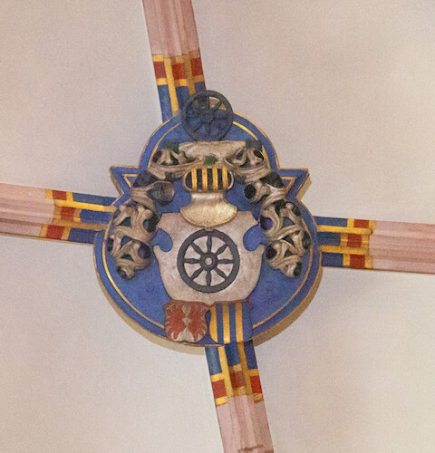 In the centre of the vaulted ceiling in front of the chapel, the coat of arms of the von Krozingen family is depicted on the vault keystone. An eight-spoked black wheel on a silver escutcheon is crowned by a clasped helmet with crest.